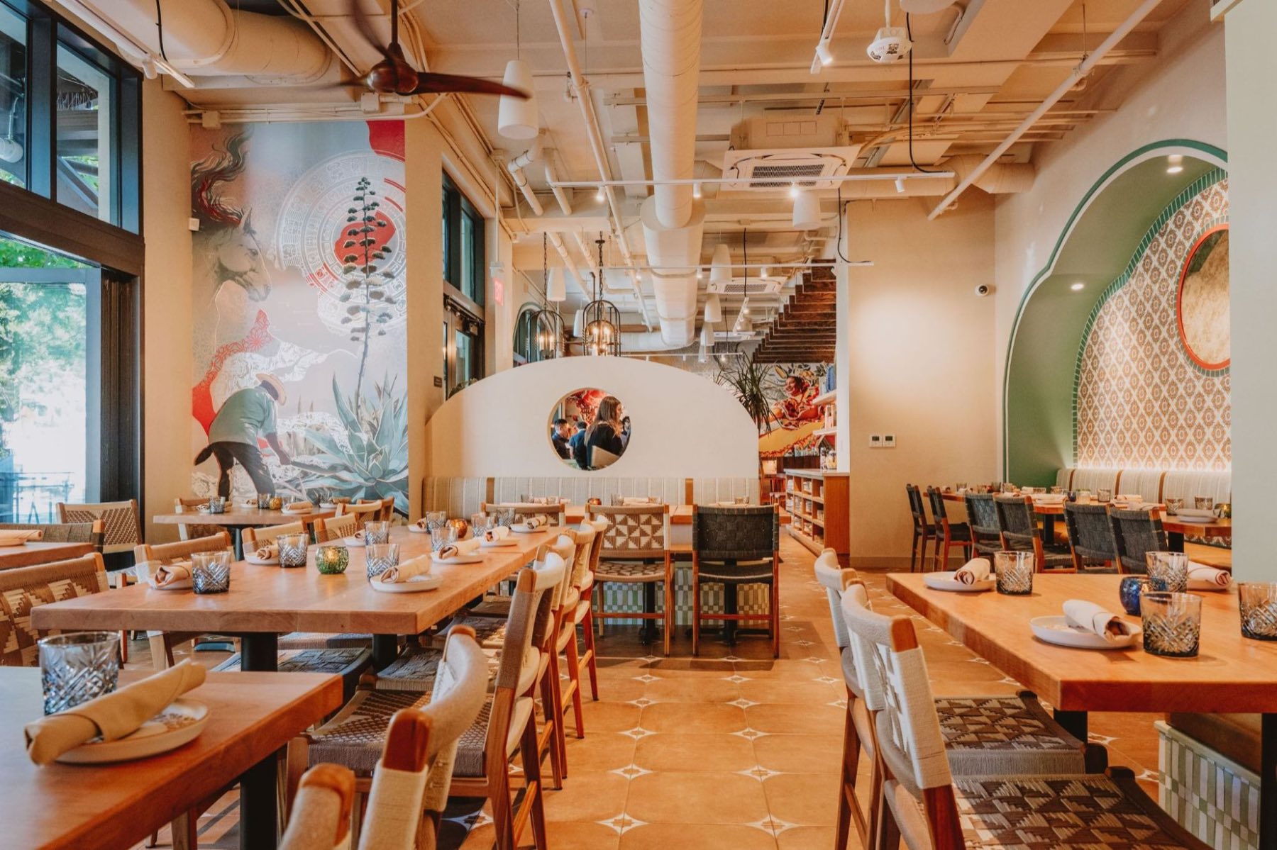 Alisios main dining room — agave and horse mural, terracotta tile floor, woven chairs and banquette seating