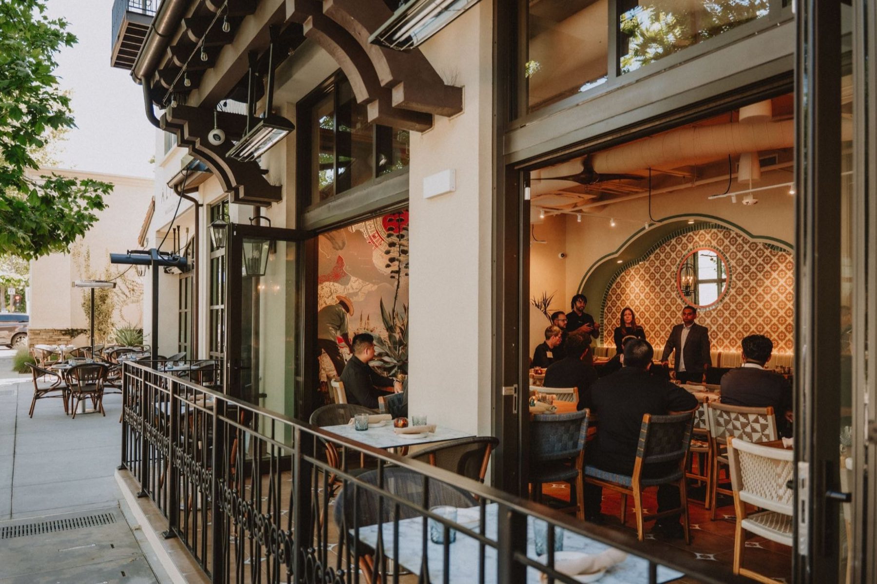 A private gathering at Alisios seen from the sidewalk terrace through open glass doors