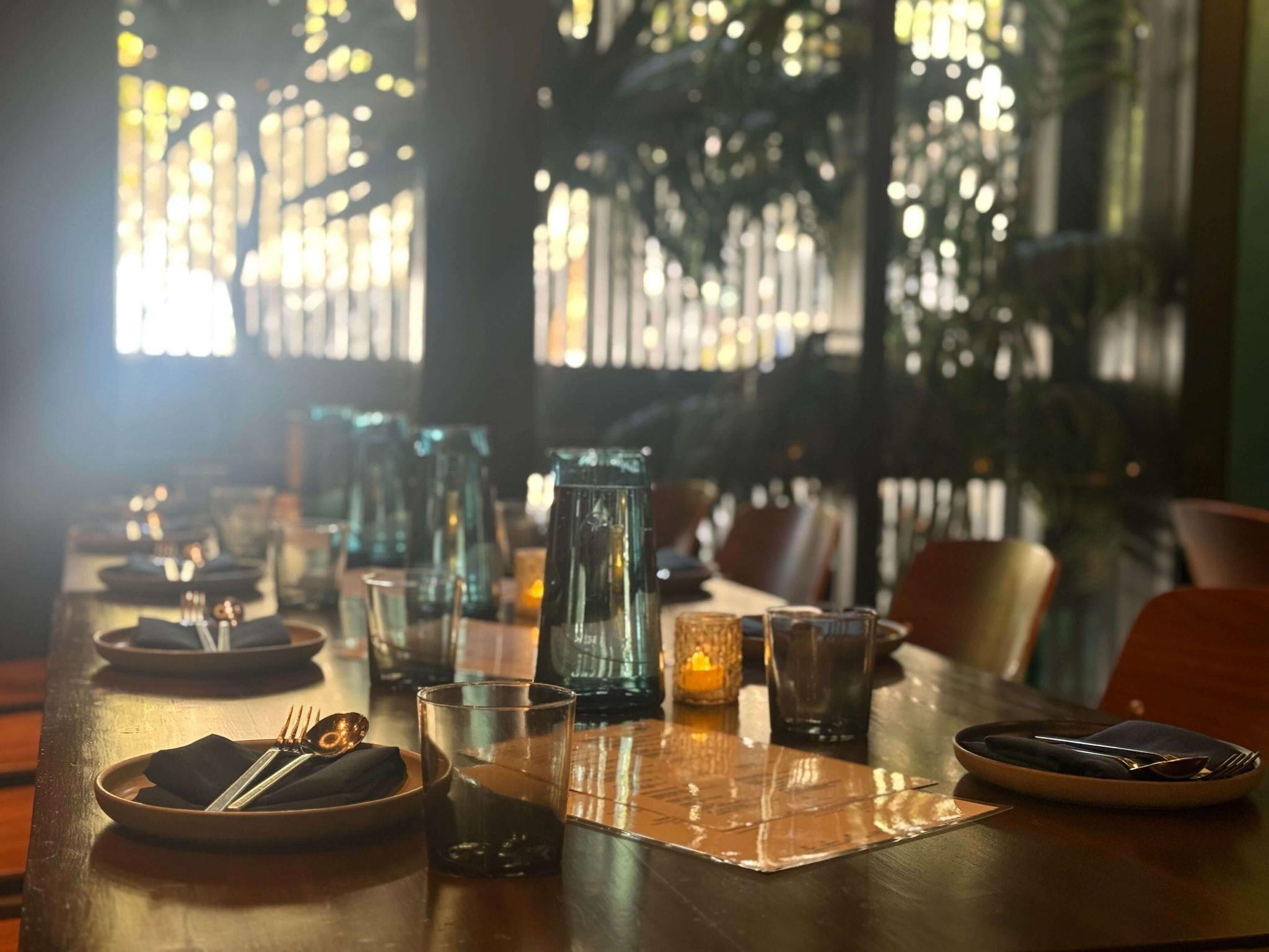 Teakwood — full dining room with teal banquettes, ring chandelier, and fish mural